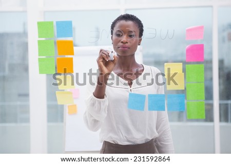 Businessman with short hair writing on clear board in the office