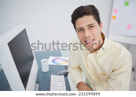 Handsome businessman smiling at camera in his office