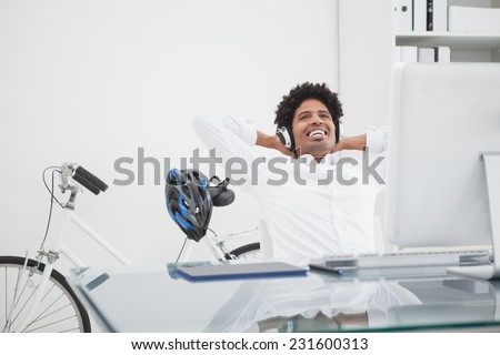Relaxed designer with headphones leaning back in his chair in his office