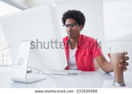 Concentrated businessman with milkshake using computer in his office