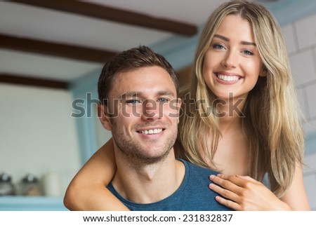 Cute couple smiling at camera at home in the kitchen