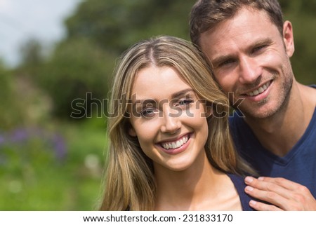 Cute couple smiling at camera at home in the garden