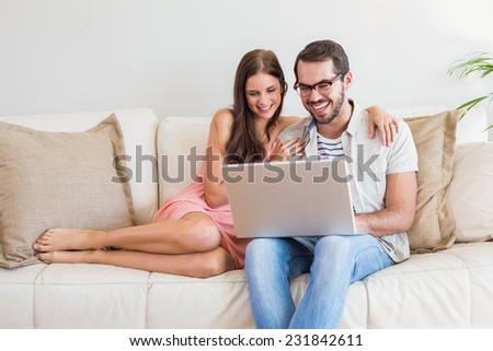 Hipster couple using laptop on couch at home in the living room