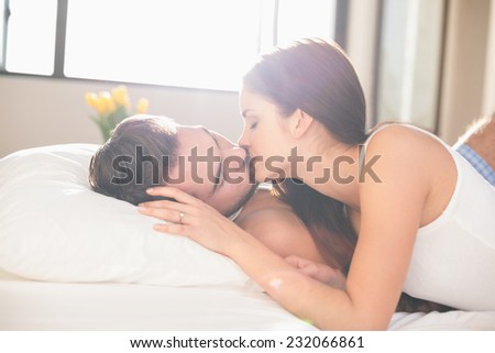 Young couple kissing in bed at home in bedroom