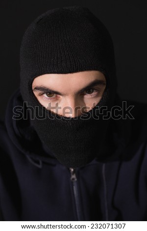 Portrait of burglar wearing a balaclava on black background