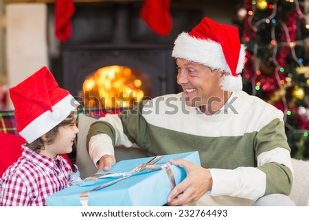 Son giving father a christmas gift on the couch at home in the living room