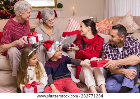 Multi generation family exchanging presents on sofa at home in the living room