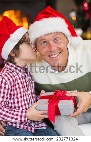 Son kissing his father after receiving a christmas gift at home in the living room