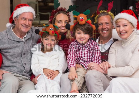Multigeneration family wearing santa hats on the couch at home in the living room