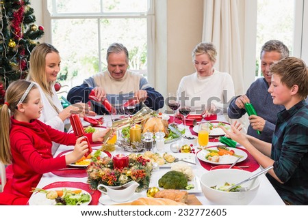 Family pulling christmas crackers at the dinner table at home in the living room