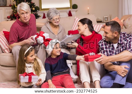 Multi generation family exchanging presents on couch at home in the living room