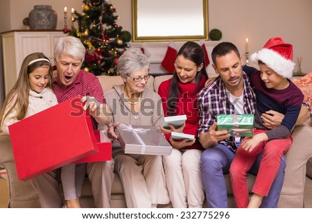 Multi generation family opening gifts on sofa at home in the living room