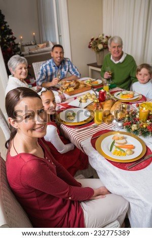 Festive family smiling at camera during christmas dinner at home in the living room