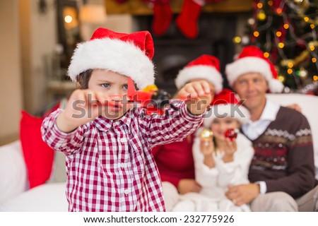 Boy playing with toy airplane in front of his family on couch at home in the living room