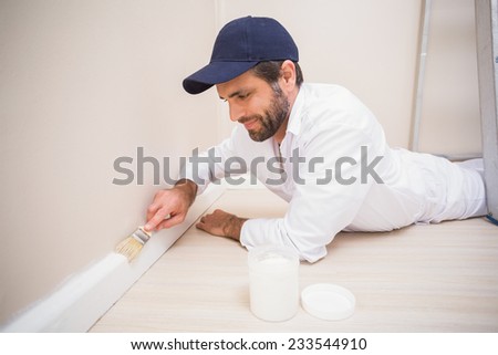 Painter painting the skirting boards in a new house