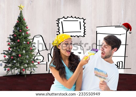 Happy young couple painting together and laughing against living room sketch at christmas