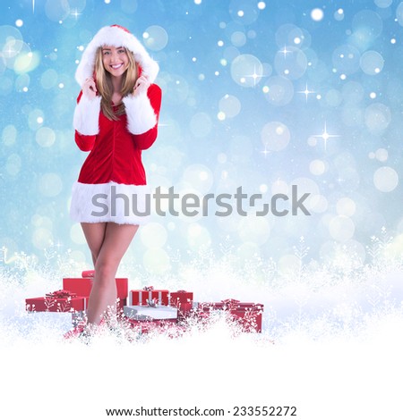 Pretty santa girl smiling at camera against blue abstract light spot design