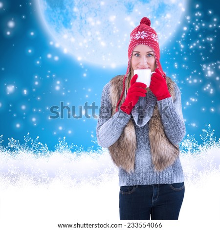 Woman in winter clothes holding a mug against blue background with vignette