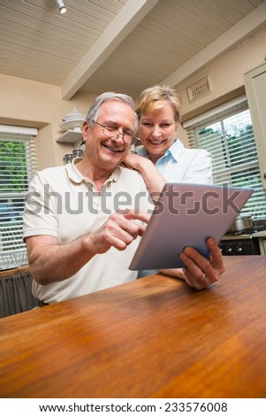 Senior couple looking at tablet pc together at home in the kitchen