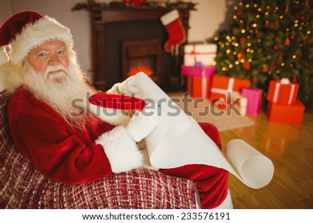 Smiling santa claus writing his list on scroll at home in the living room