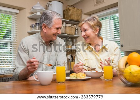 Senior couple having breakfast together at home in the kitchen