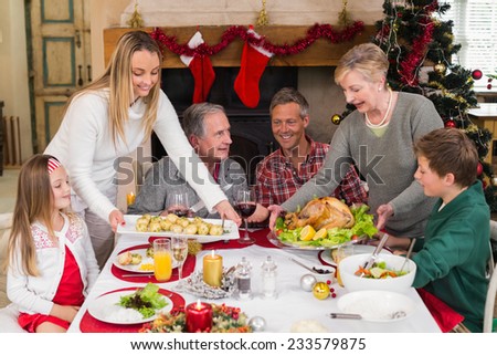 Two women serving christmas dinner to their family at home in the living room