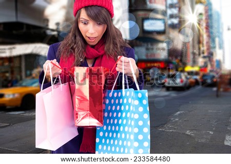 Shocked brunette opening gift bag against blurry new york street