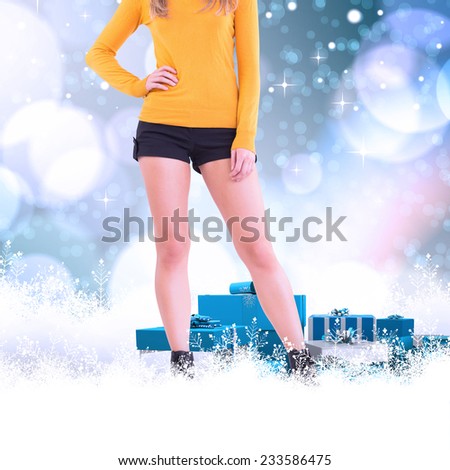 Lower half of woman in boots and shorts against light glowing dots on blue
