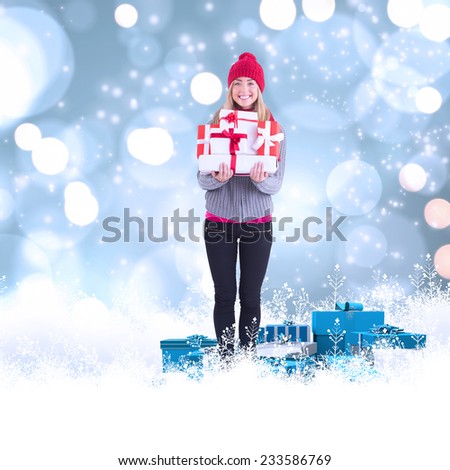 Festive blonde holding pile of gifts against white glowing dots on blue