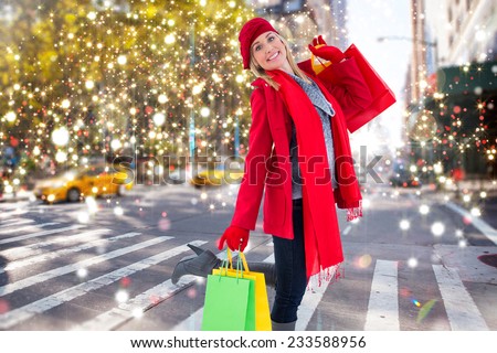 Happy blonde in winter clothes holding shopping bags against blurry new york street