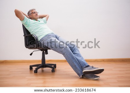 Mature man leaning back in swivel chair at home in the living room