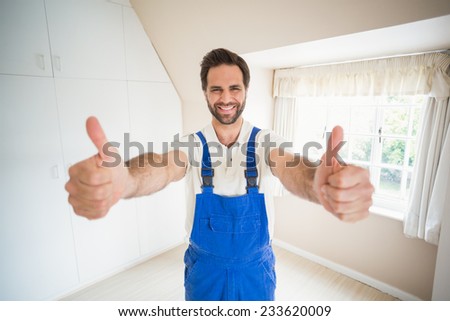 Handyman smiling at camera showing thumbs up in a new house