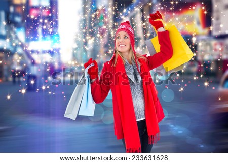 Blonde in winter clothes holding shopping bags against blurry new york street