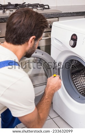 Handyman fixing a washing machine in the kitchen