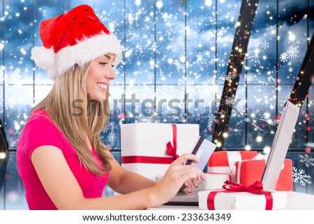 Festive blonde shopping online with laptop against glittering lights in room