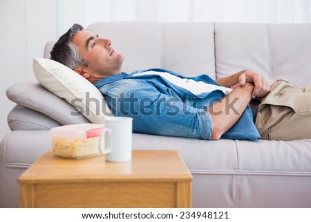 Relaxed man lying on the couch at home in the living room