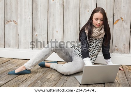 Pretty hipster using her laptop against bleached wooden planks
