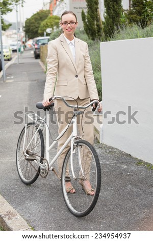 Young businesswoman standing with bike outside in the city