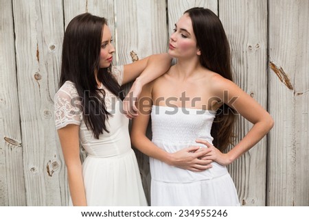 Pretty friends posing in white dresses against bleached wooden planks