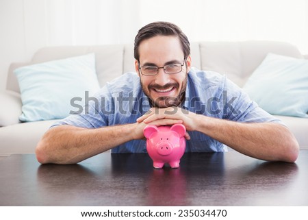 Smiling man laying on the piggy bank in the living room