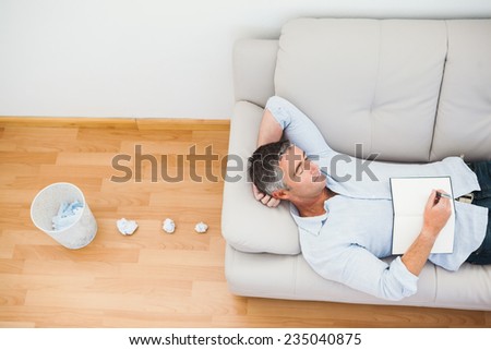Man resting on couch with writer block at apartment