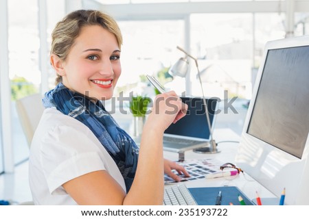 Smiling photo editor using computer in office