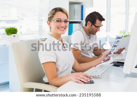 Photo editor holding contact sheet and smiling at camera in her office
