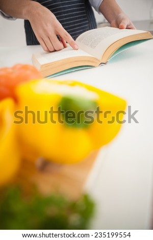 Woman following a recipe in book at home in the kitchen