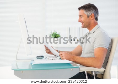 Happy man reading document at desk in his office