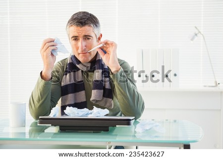 Sick man taking his temperature in his office