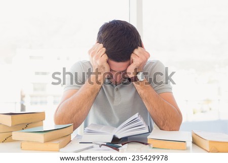 Stressed casual businessman studying at his desk in his office