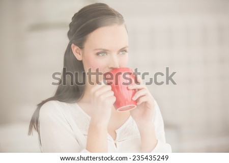 Pretty brunette drinking cup of coffee at home in the living room