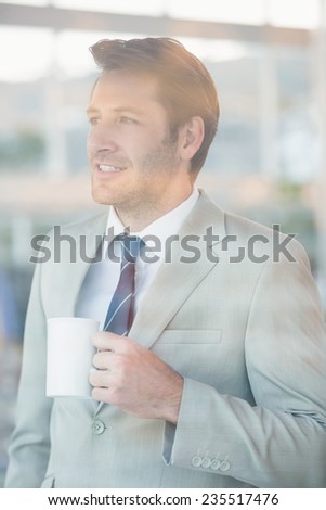 Handsome businessman holding cup of coffee at work