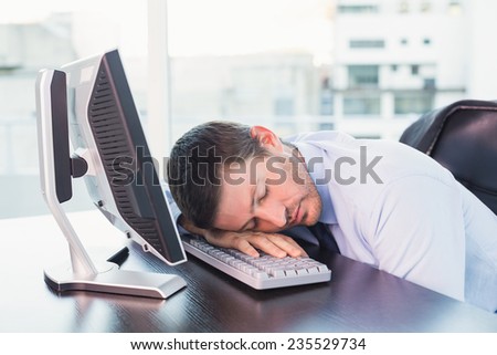 Exhausted businessman sleeping at his desk in his office